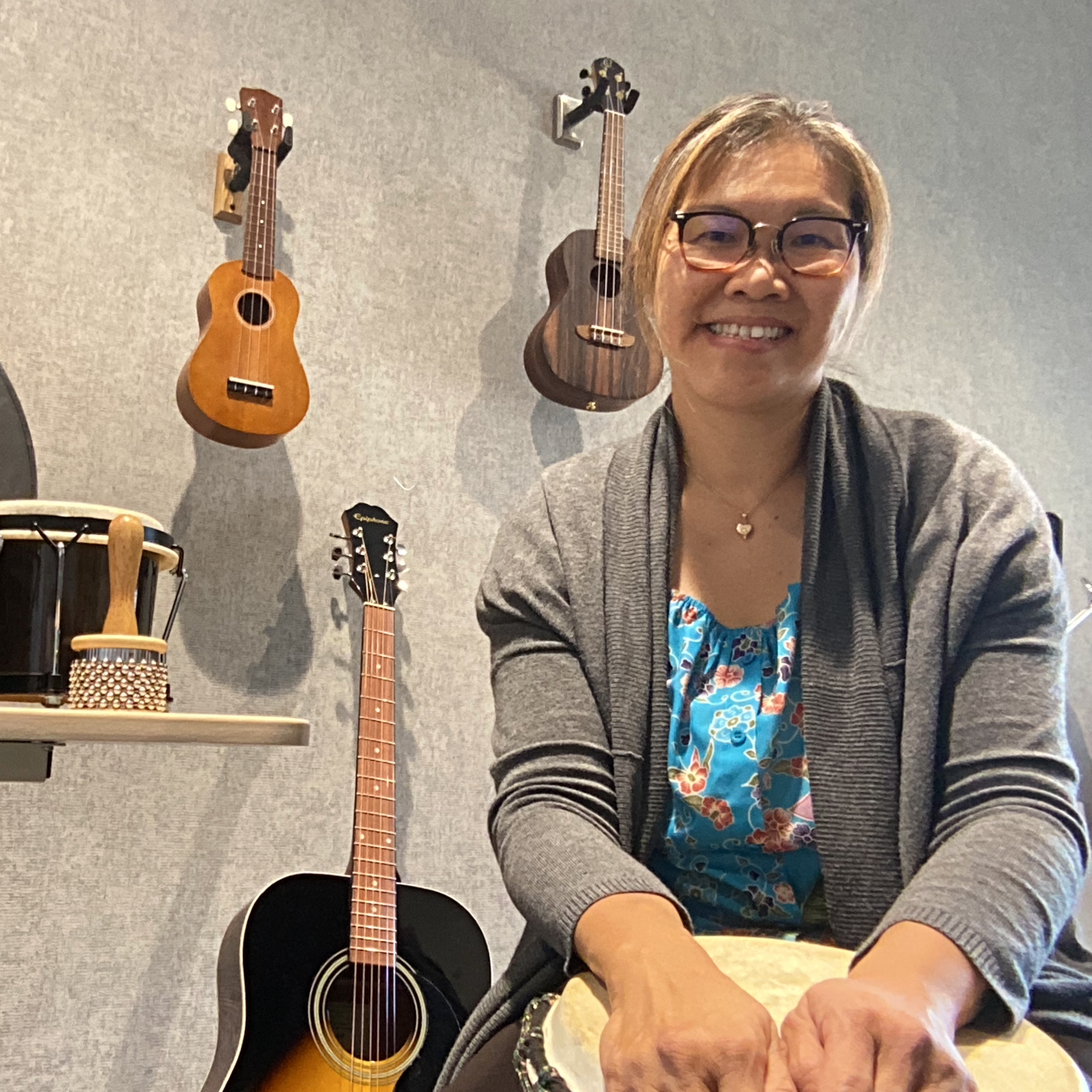 A person surrounded by musical instruments and smiling