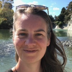 A head shot of a person smiling beside a river